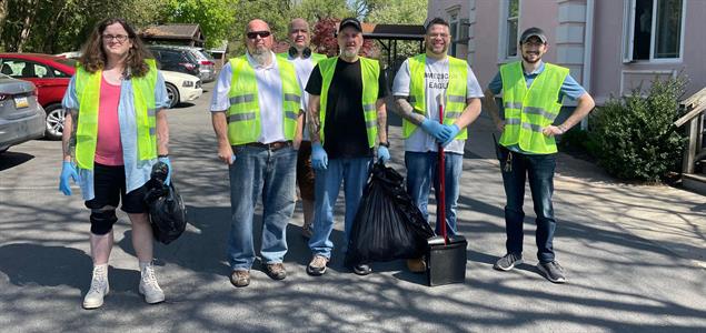 A group of people wearing vests and gloves and holding bags of trash