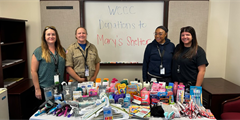 Staff members standing next to the donations for Mary's Shelter.