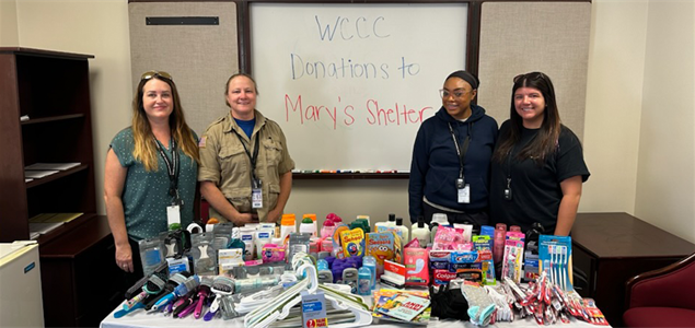 Staff members standing next to the donations for Mary's Shelter.