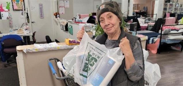 A woman holds a bag of donated items at Ruth's Place Women's Shelter