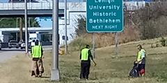 Three reentrants pick up litter along the side of the road