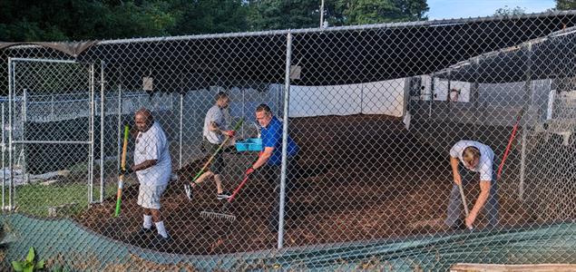 Reentrants from Harrisburg CCC and York CCC shovel out a pen at Canine Rescue of Central PA