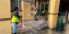 Two people clean a sidewalk in Pittsburgh.