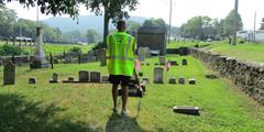 A man mows the lawn at a cemetery