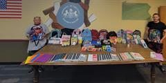 Two people stand around a table full of school supplies