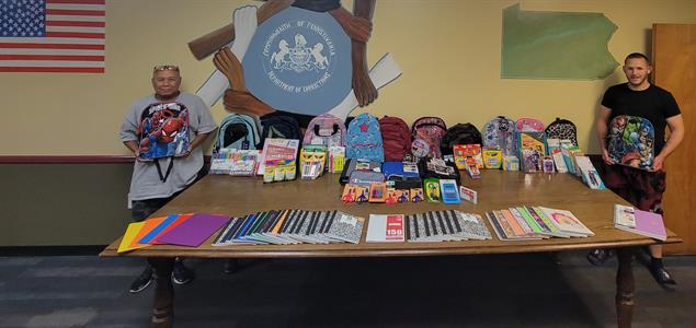 Two people stand around a table full of school supplies