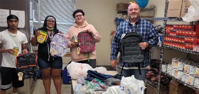 Four people holding backpacks and school supplies