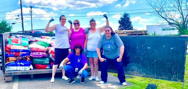 Five women stand next to a truck load of donated pet food
