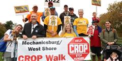 A group of people standing holding signs supporting the 2022 CROP Walk