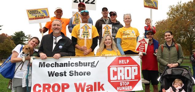 A group of people standing holding signs supporting the 2022 CROP Walk