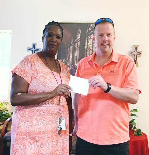 Deputy Superintendent Paul Ennis gives a check to a representative from the Mercy Center