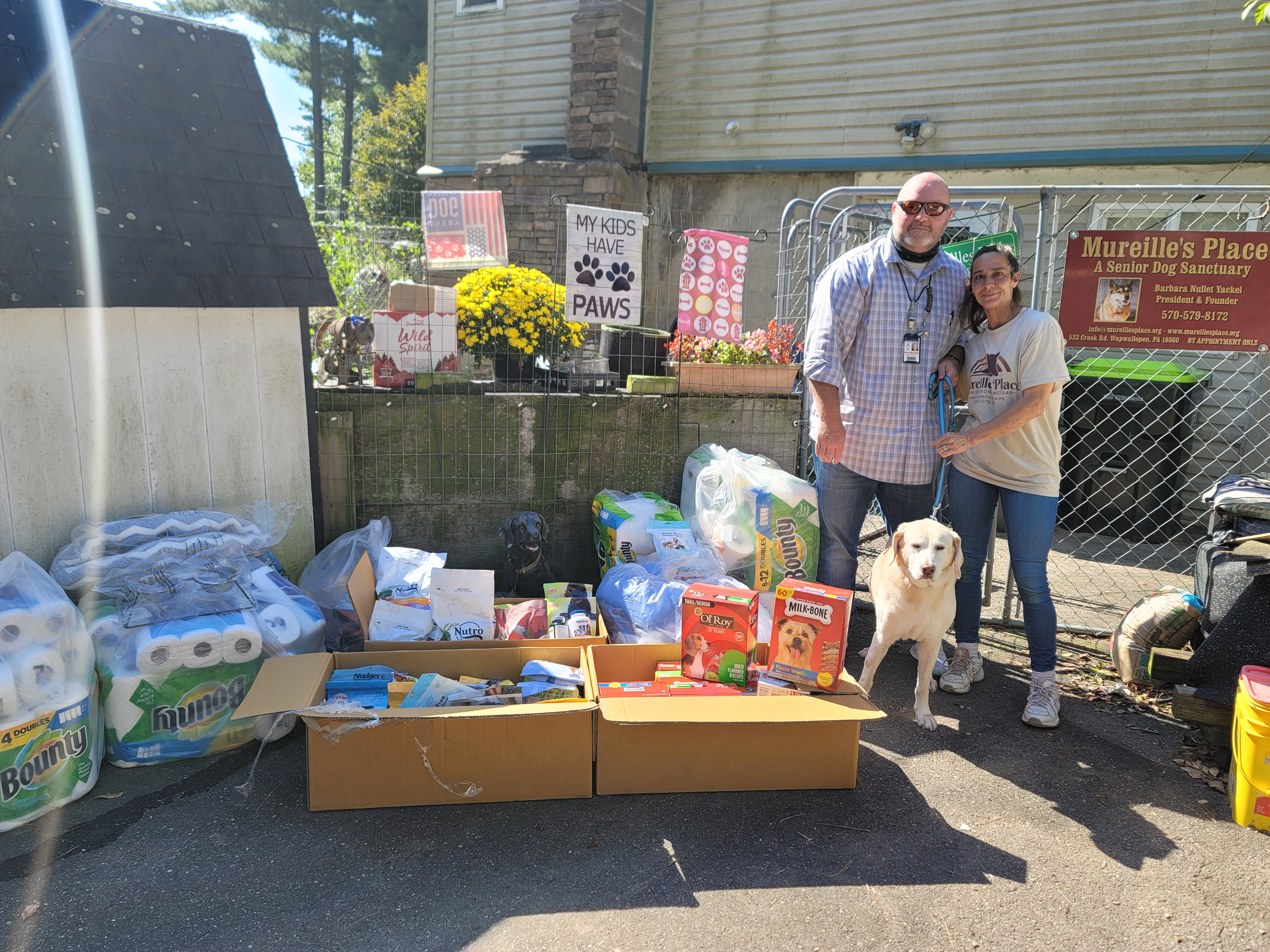 Two people and a dog stand by donations