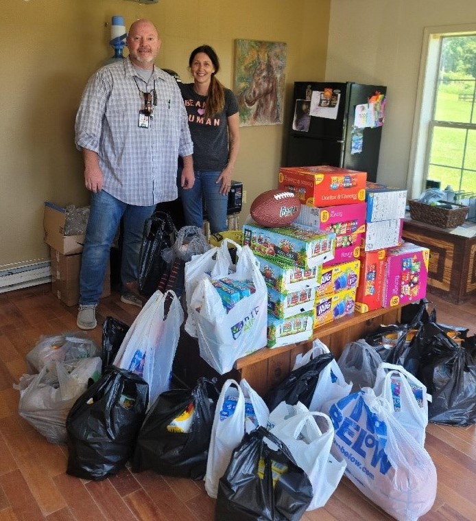 Two people stand with bags of donated items