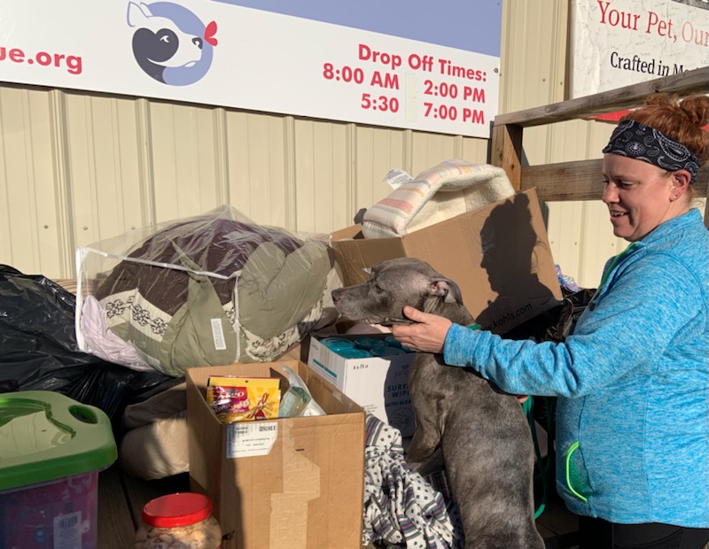 An employee and dog stand next to donations