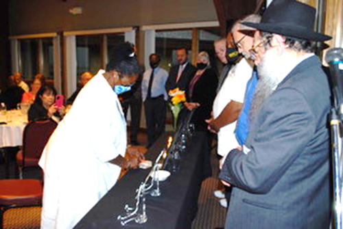 A reverend lights a candle in front of other chaplains