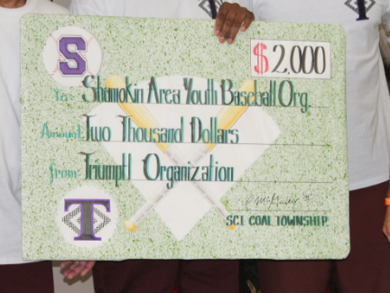 Incarcerated individuals at SCI Coal Township hold a giant check to the Shamokin Area Youth Baseball Organization.