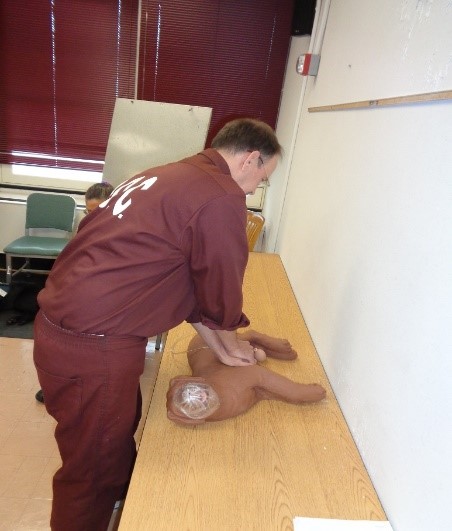 An inmate practices CPR on a fake dog