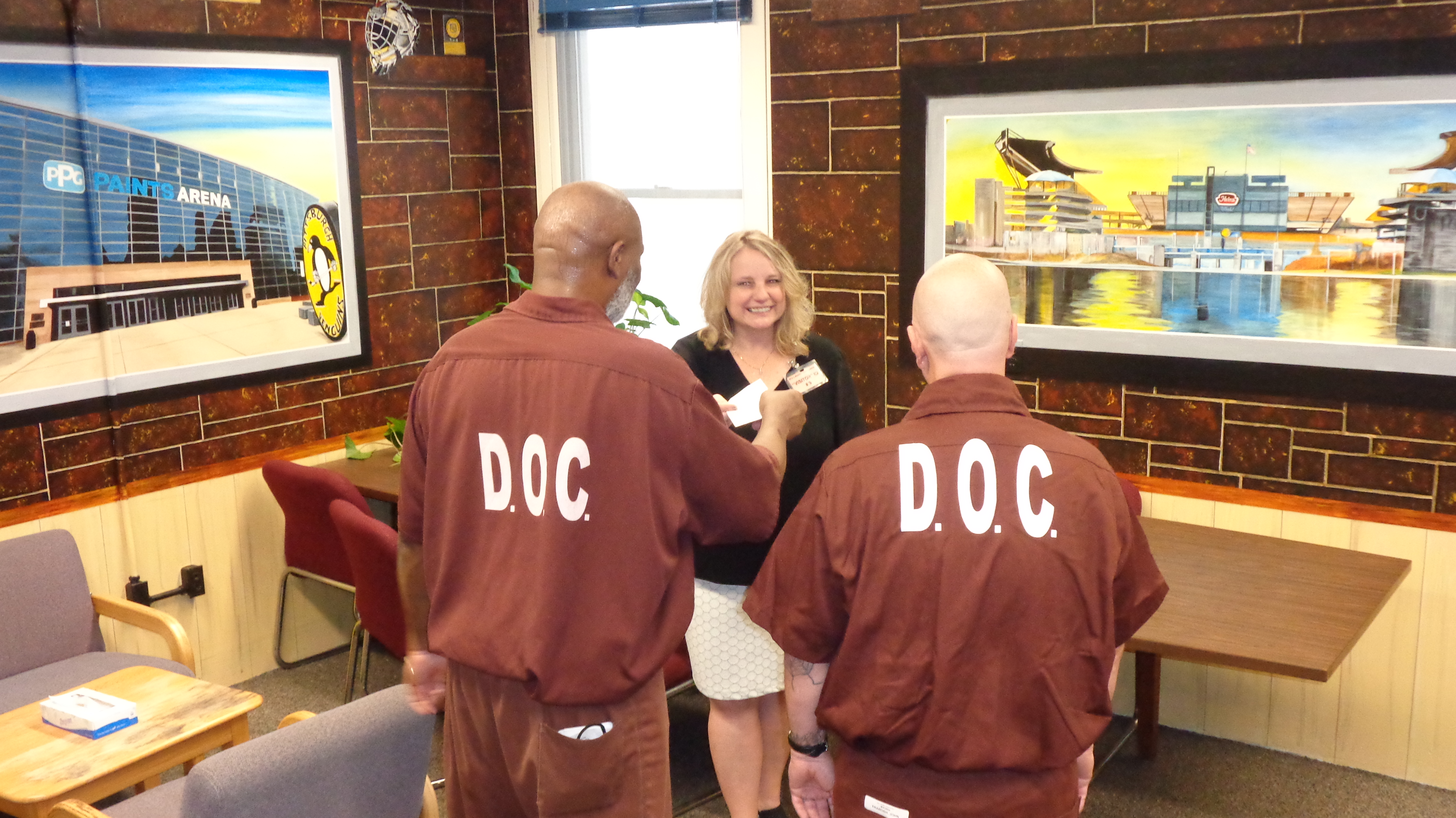 Two inmates give a woman a check donation