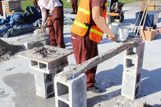 Inmates apply mortar and bricks
