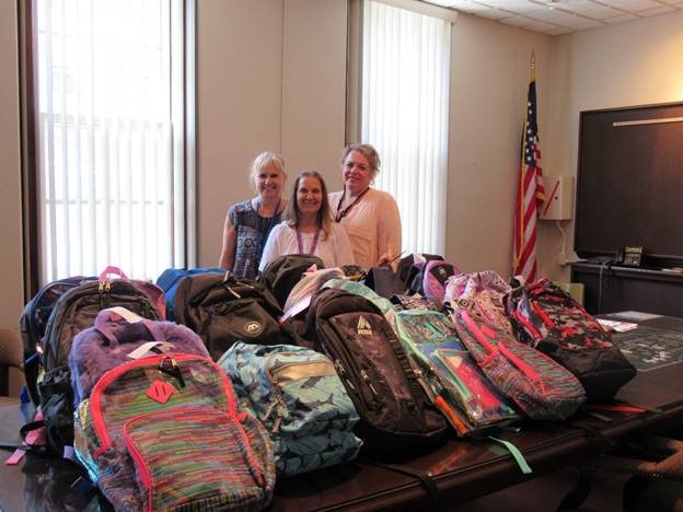 Waymart employees pose behind backpacks they donated