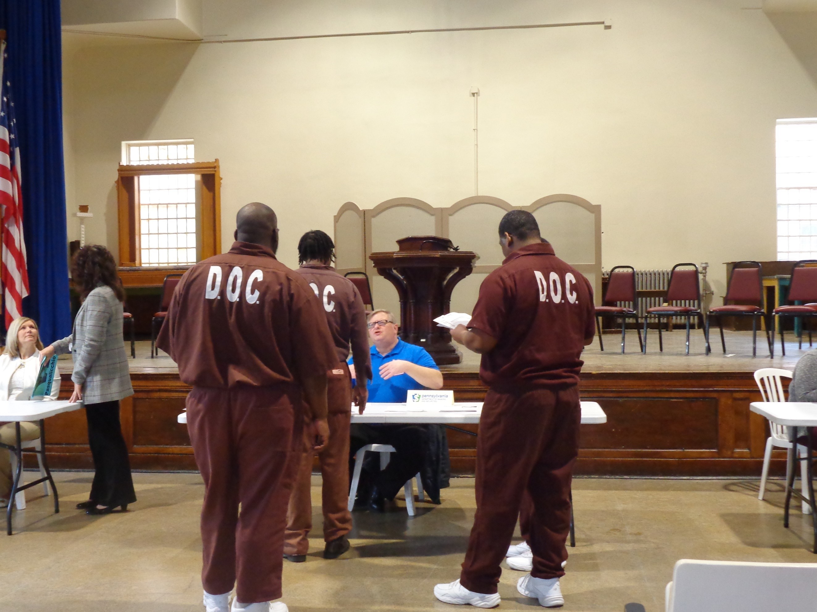 WAM - 2019 March 27 Career and Reentry Fair - inmates at table talking to man in blue shirt.jpg