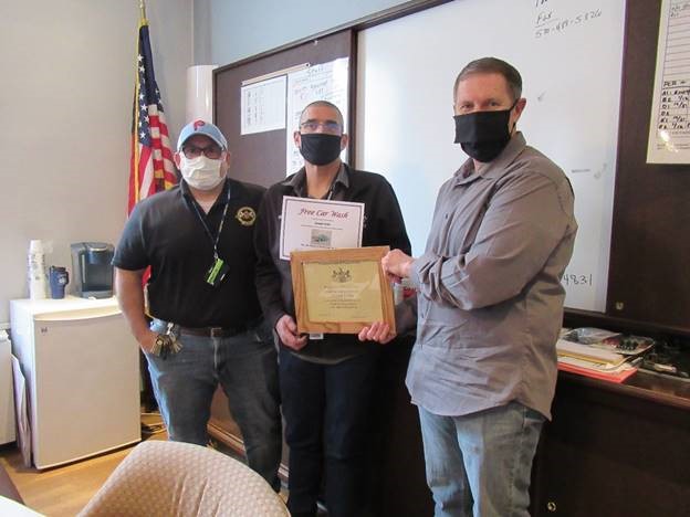 A DOC deputy receives a certificate from two DOC leaders