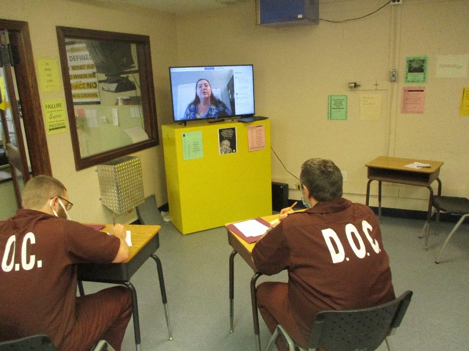 Two inmates watch a virtual presentation