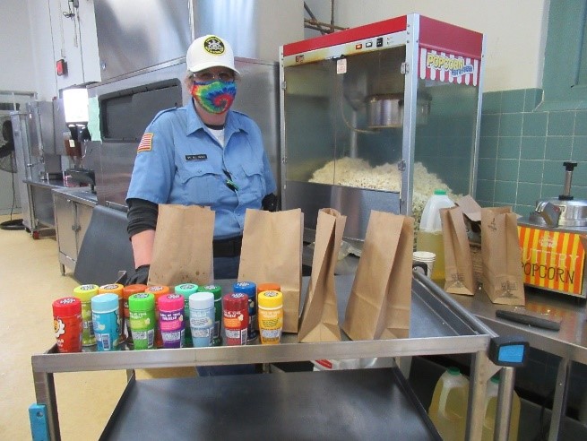 An employee stands with a popcorn machine
