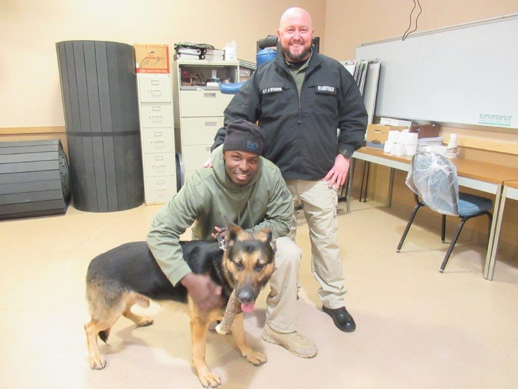 Two SCI Waymart employees stand with Klif, a K9 agent, at Waymart's career day for Honesdale High School