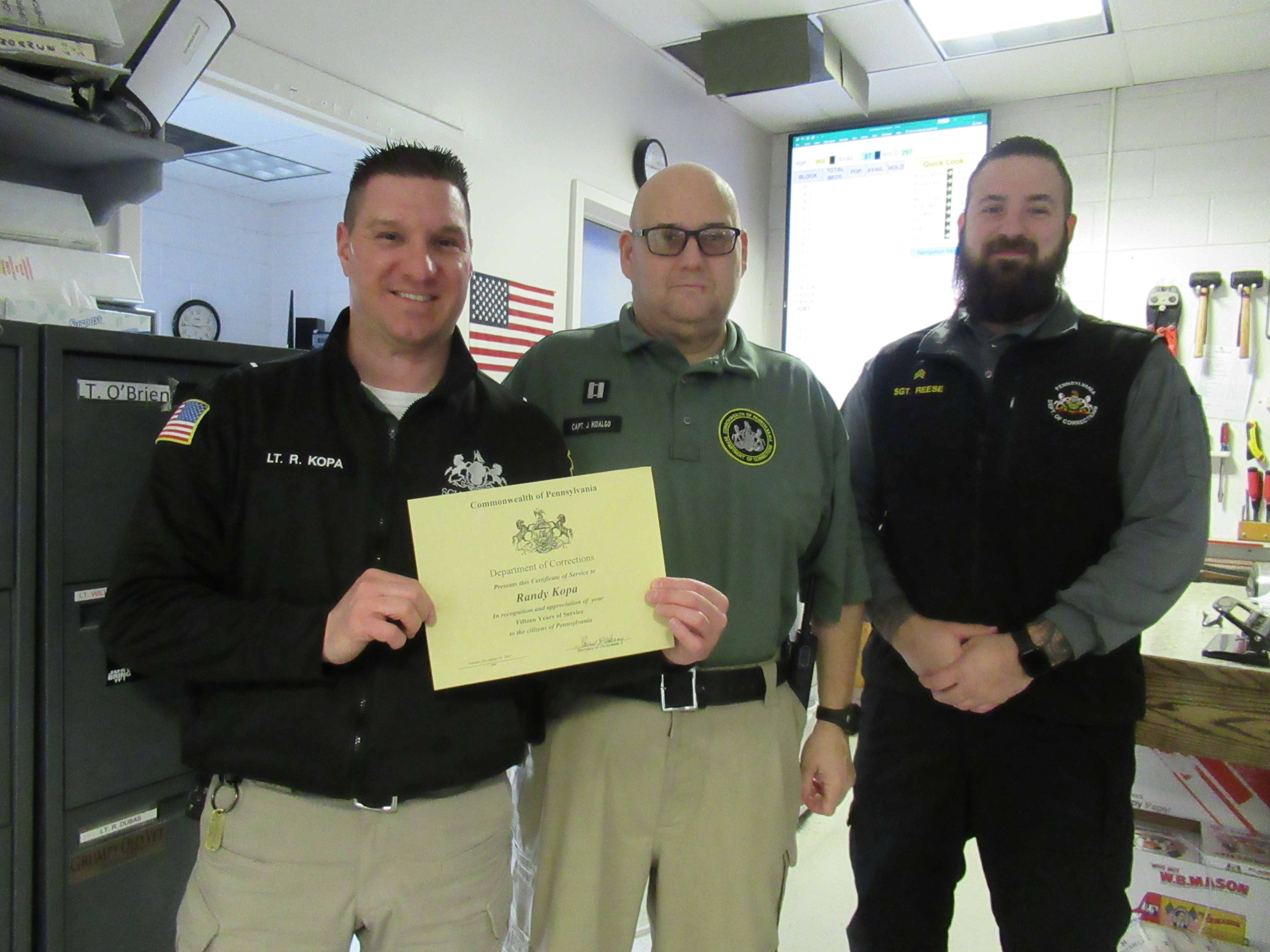 Lieutenant Randy Kopa holds a certificate with Captain J. Hidalgo and Sergeant C. Reese.