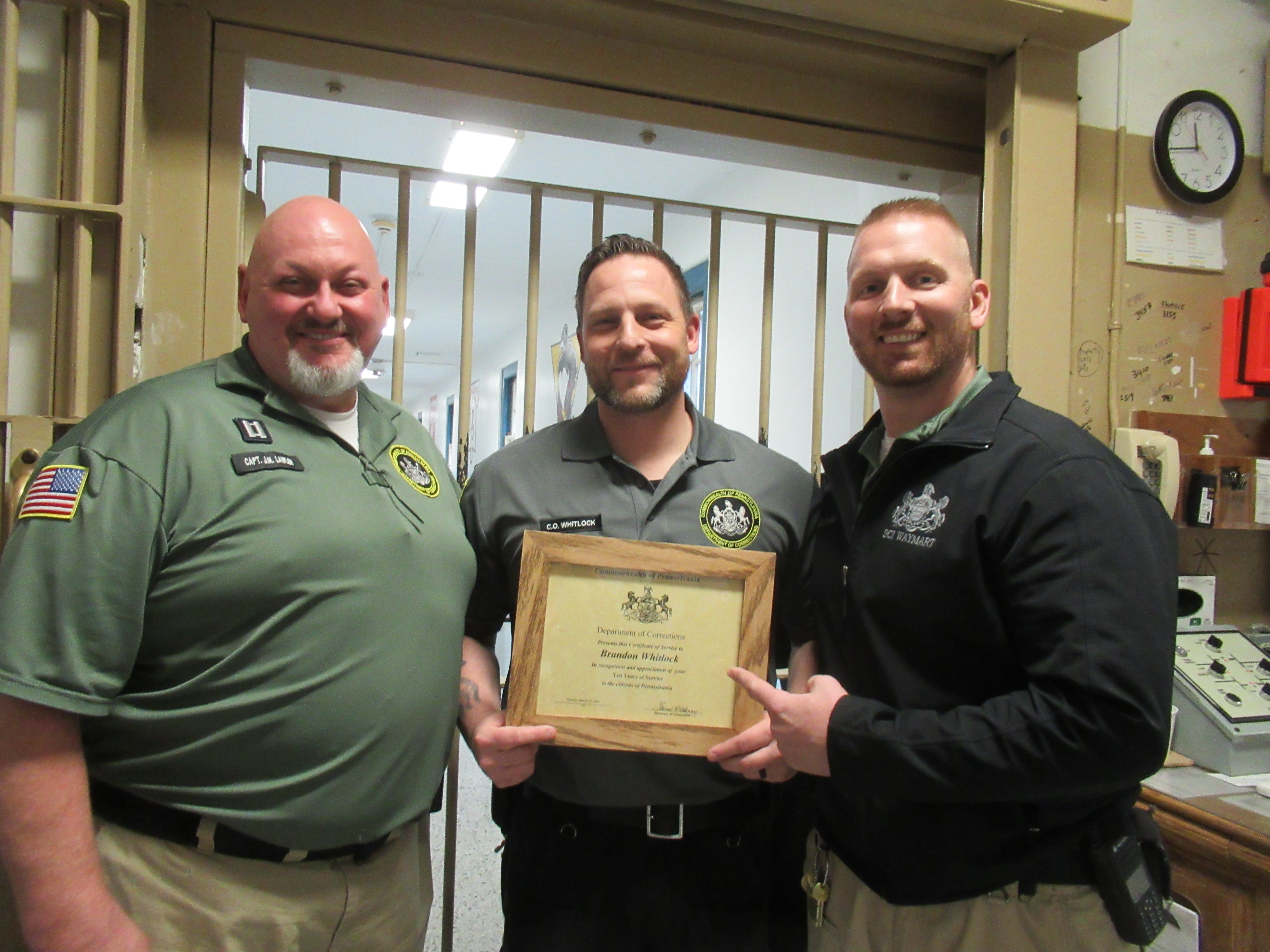 CO Brandon Whitlock holds a certificate while standing with Captain J. Lawler and Lieutenant R. Gardner
