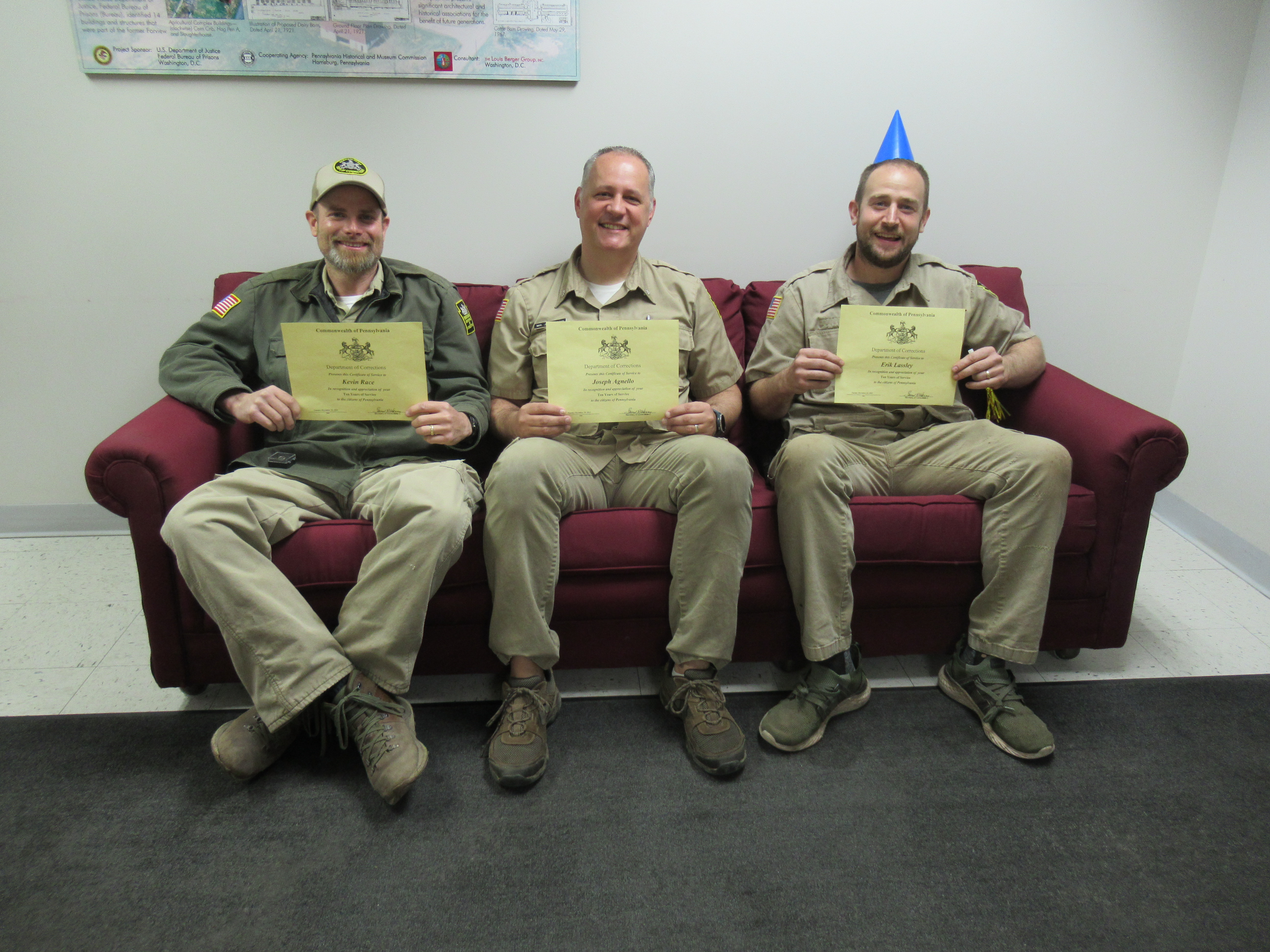 Kevin Race, Joe Agnello and Erik Lassley sit on a couch holding certificates