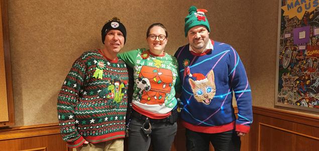 Three people wearing Christmas sweaters.