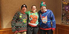 Three people wearing Christmas sweaters.