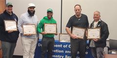 Five men holding framed certificates