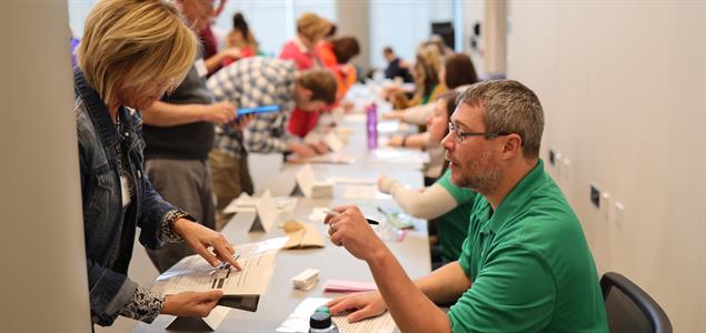 A participant in the Lackawanna County Reentry Task Force's Reentry Simulation at the University of Scranton talks with a DOC employee at a table as part of the simulation