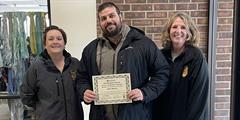 Reentry Parole Agent Marnie Sommers and Parole Agent Kaylene Carson stand with Sam Barco of the Forensic Boundary Spanner program as he holds his certificate of appreciation