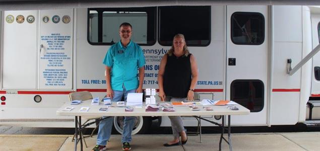 Two people stand outside the PA DMVA Mobile Outreach Van