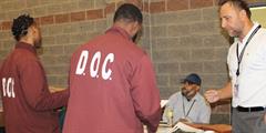 Two incarcerated individuals speak with an attendee at the SCI Albion Reentry Career Fair