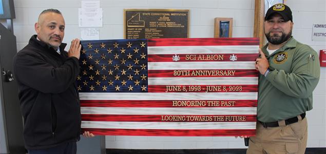 DSFM Earl Jones and Lt. Dube hold a wooden flag that Dube created in honor of Albion's 30th Anniversary.