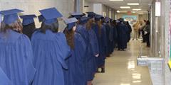 A group of incarcerated graduates stand in line to walk into their graduation ceremony