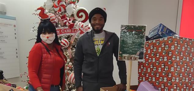 Two people stand with donated gifts
