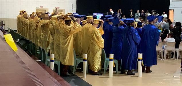 Graduates from SCI Chester in yellow and blue caps and gowns at the ceremony.