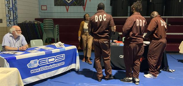 Three inmates talk to an attendee at SCI Chester's Reentry Fair