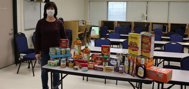 A woman stands by a table of donations