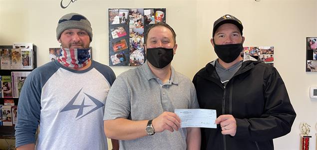 Three men stand with a check