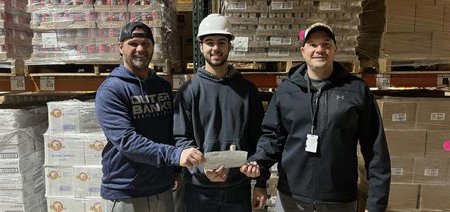 Three people holding a check