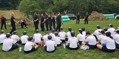 A group of kids watches a group of corrections personnel giving a presentation