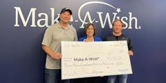 Three people holding a big check in front of a Make A Wish sign