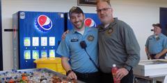 Two DOC employees stand with each other while getting bottled soda at the 10th anniversary party for SCI Houtzdale
